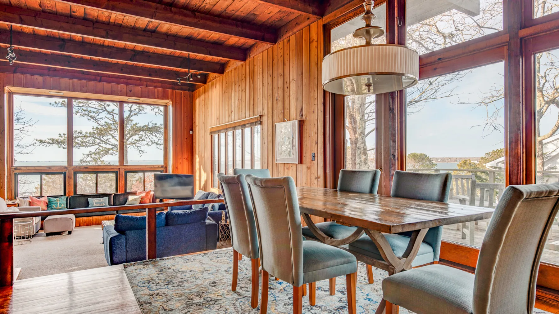 A wood-paneled dining area with a table and seating beside large windows.