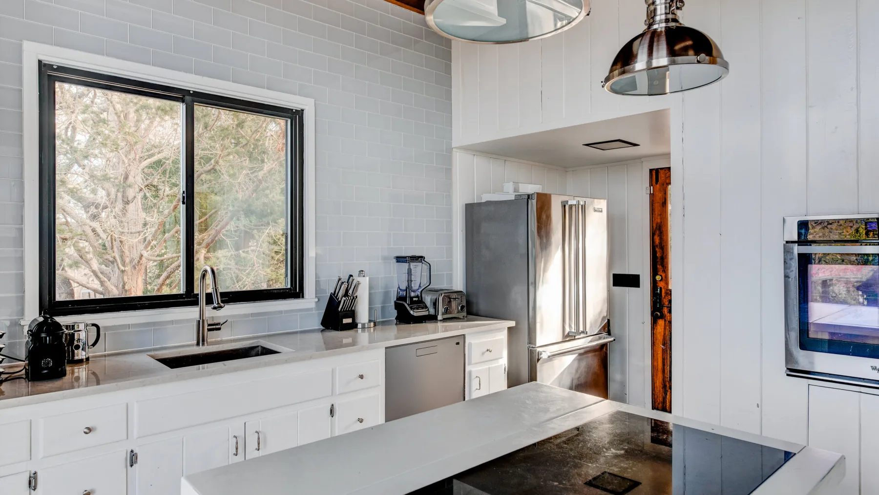 Una cocina luminosa con gabinetes blancos, una encimera larga y una ventana.