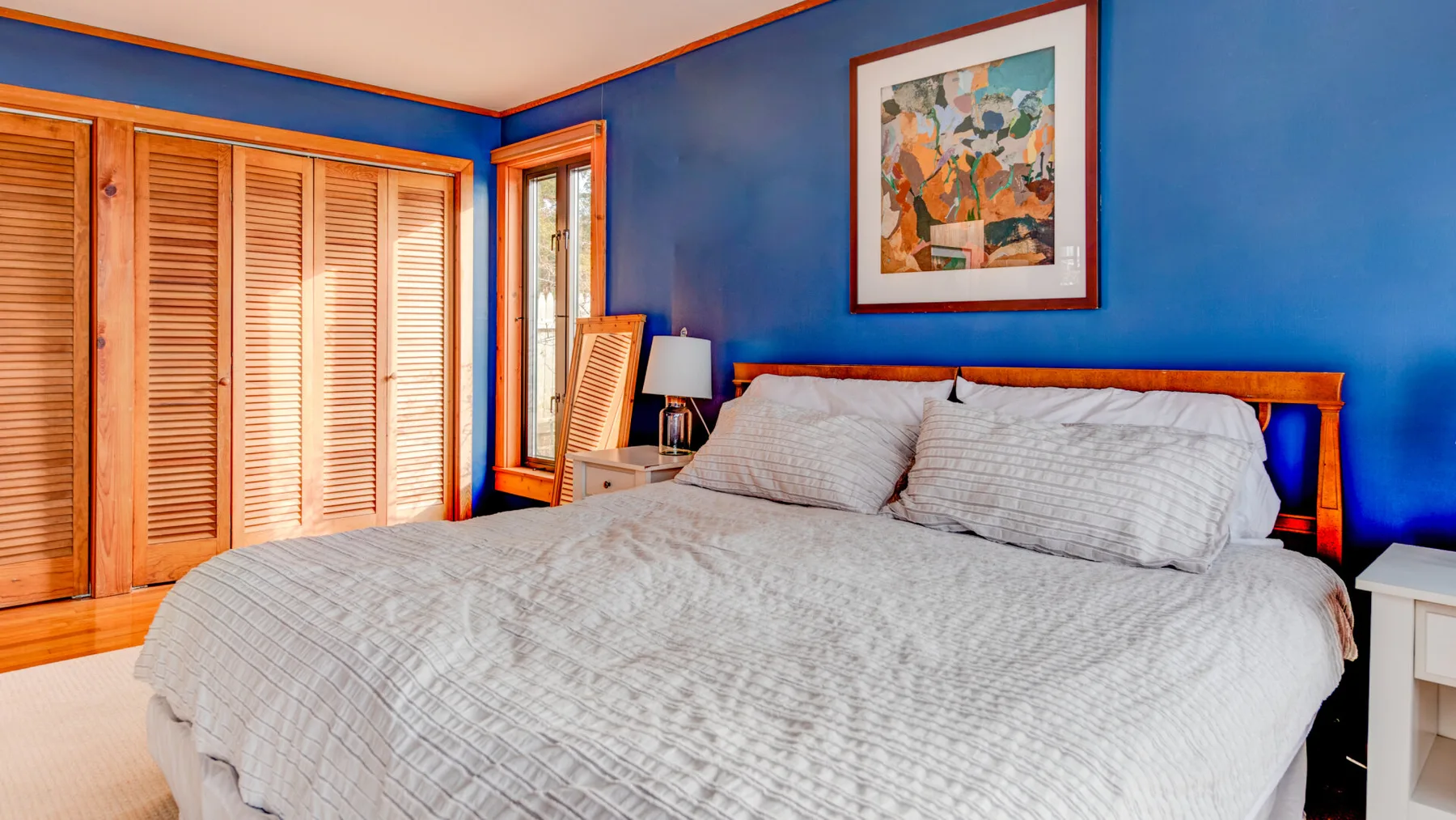 Un dormitorio con una cama grande, paredes azules y armarios de madera con celosías.