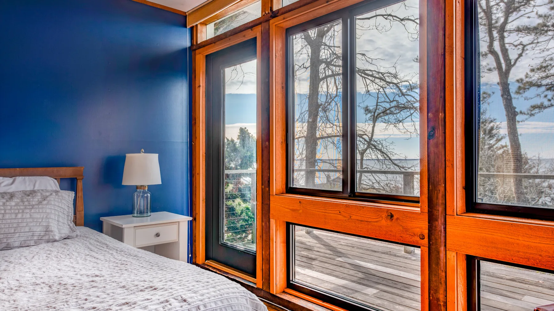 Un dormitorio con una cama junto a grandes ventanas con vista al agua.