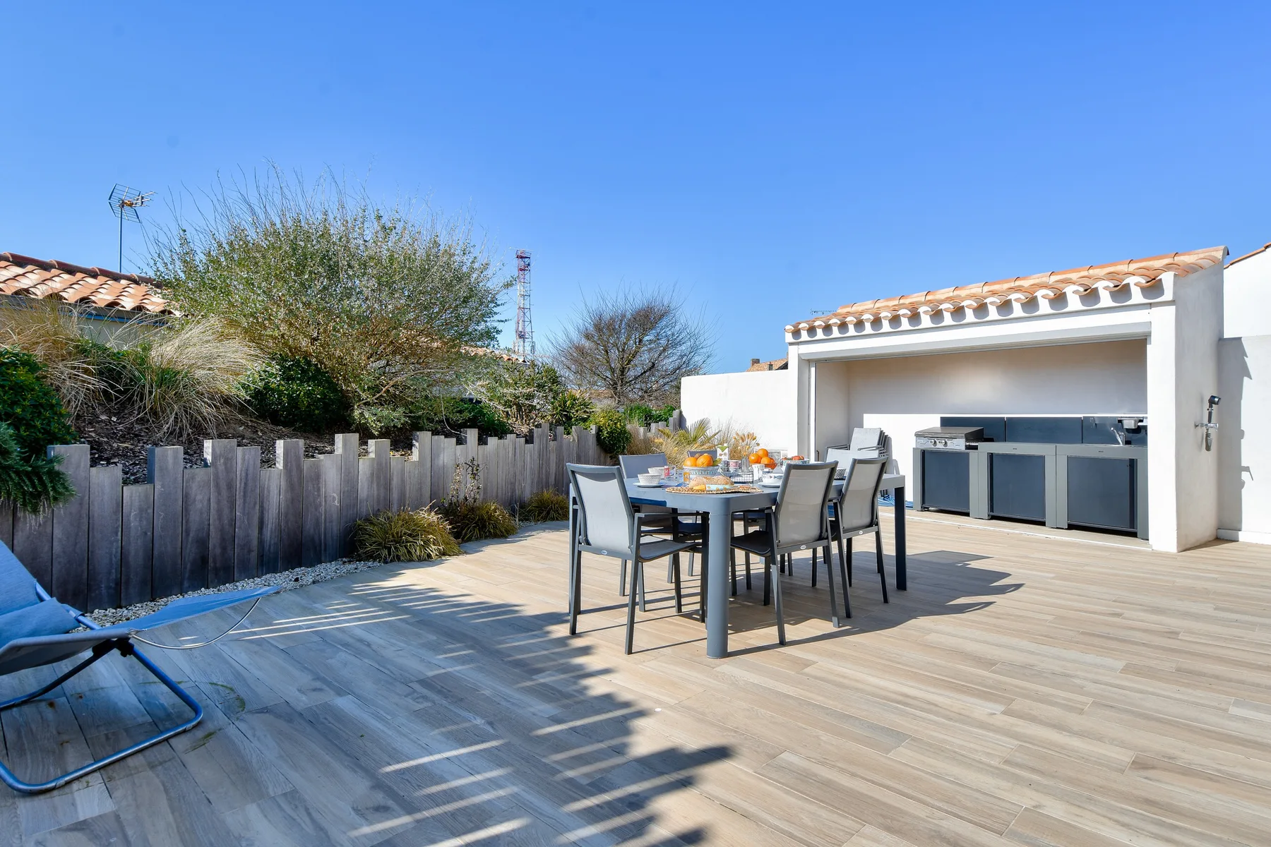 An outdoor dining area on a spacious deck beside a built-in counter.
