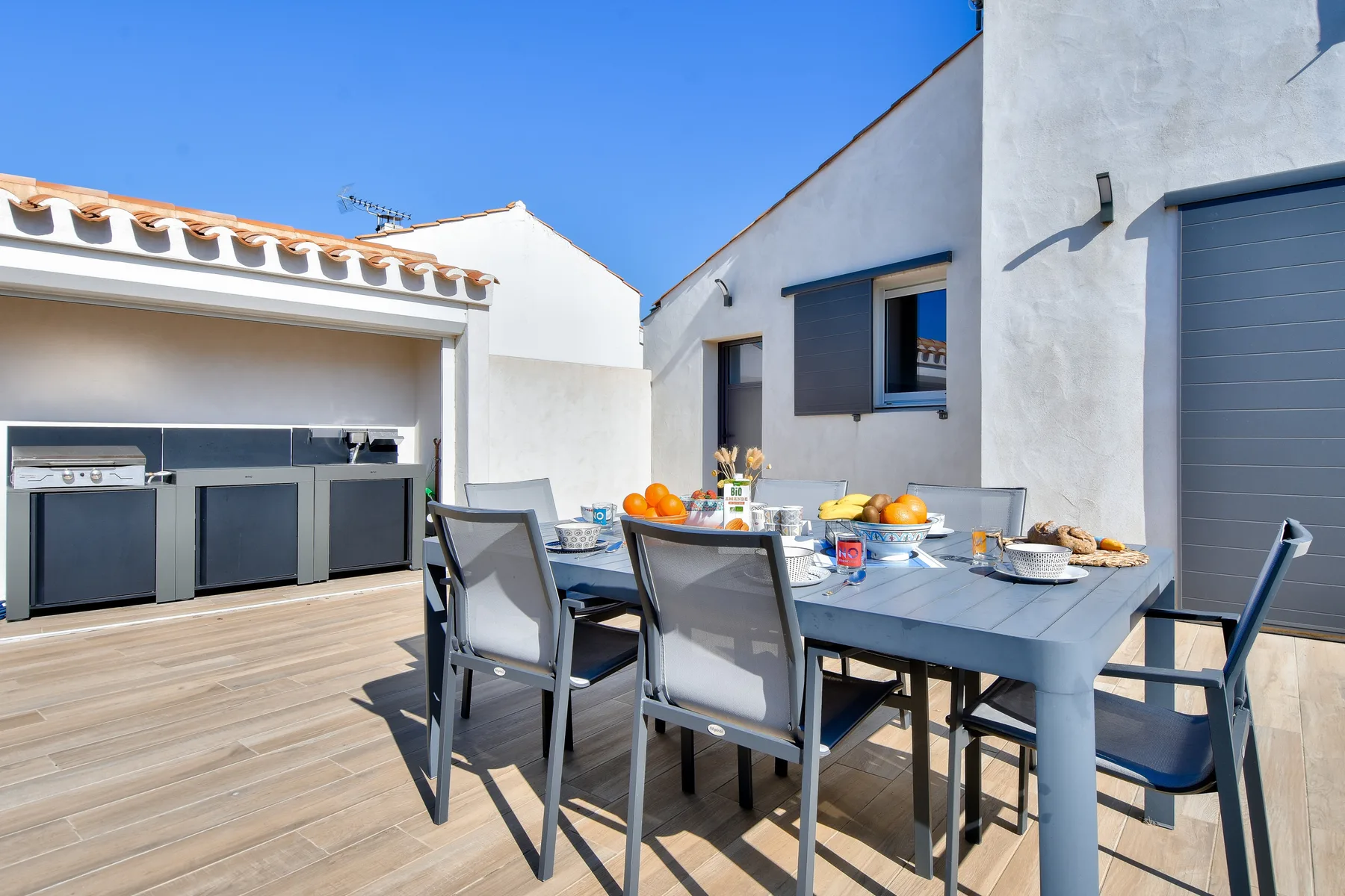 An outdoor dining area with a table set beside a built-in grill.