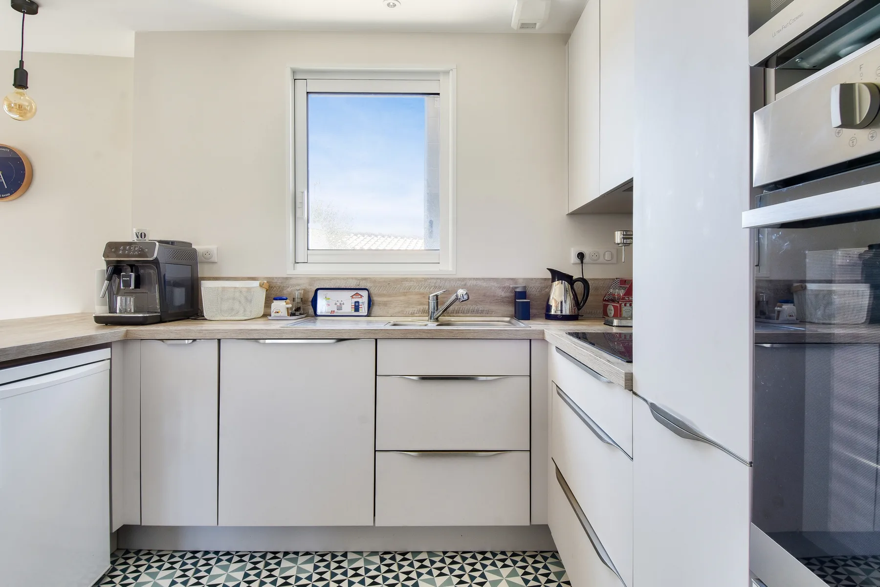 A bright kitchen with white cabinets, a countertop, and a window.