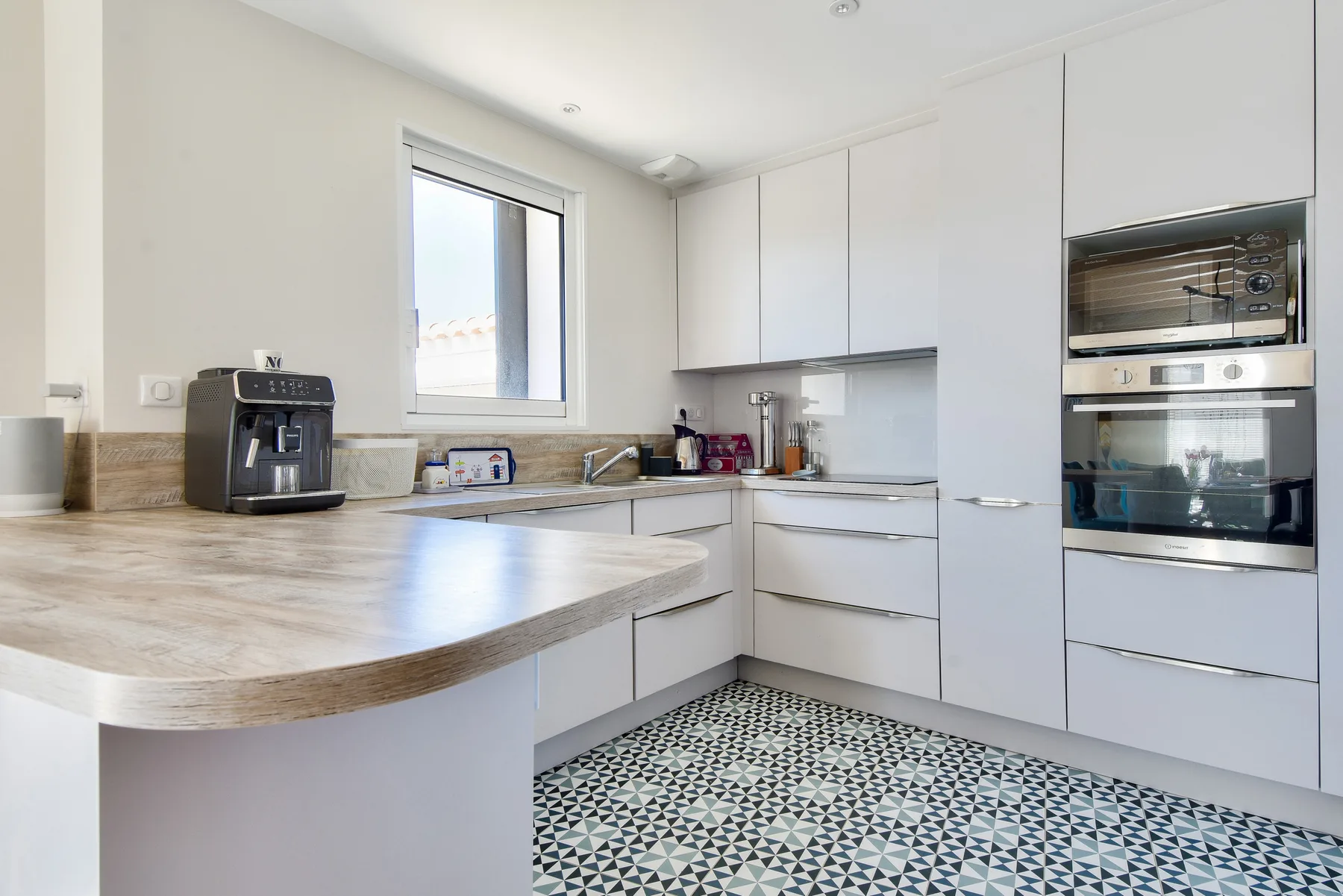 A bright kitchen with white cabinets, countertop space, and built-in appliances.