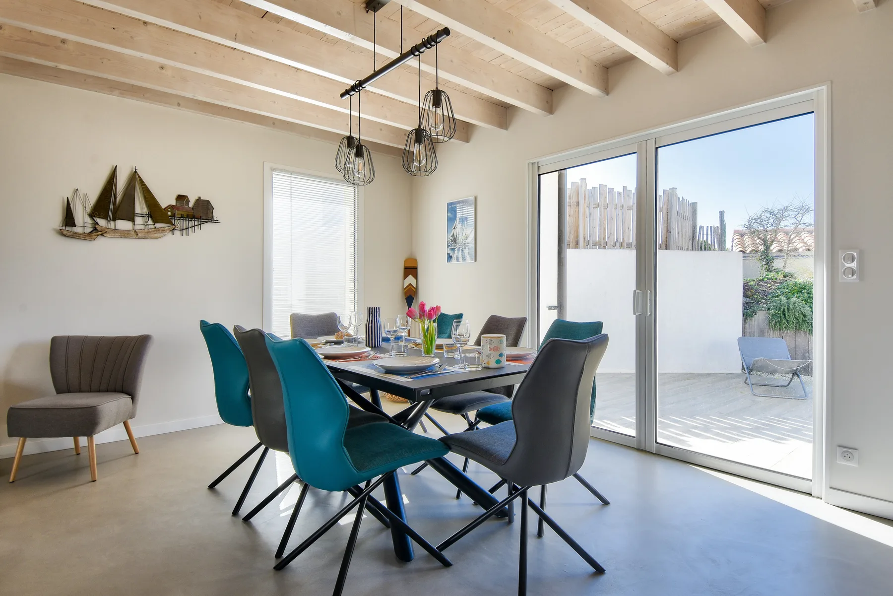 A dining area with a table and colorful seating beside large sliding glass doors.