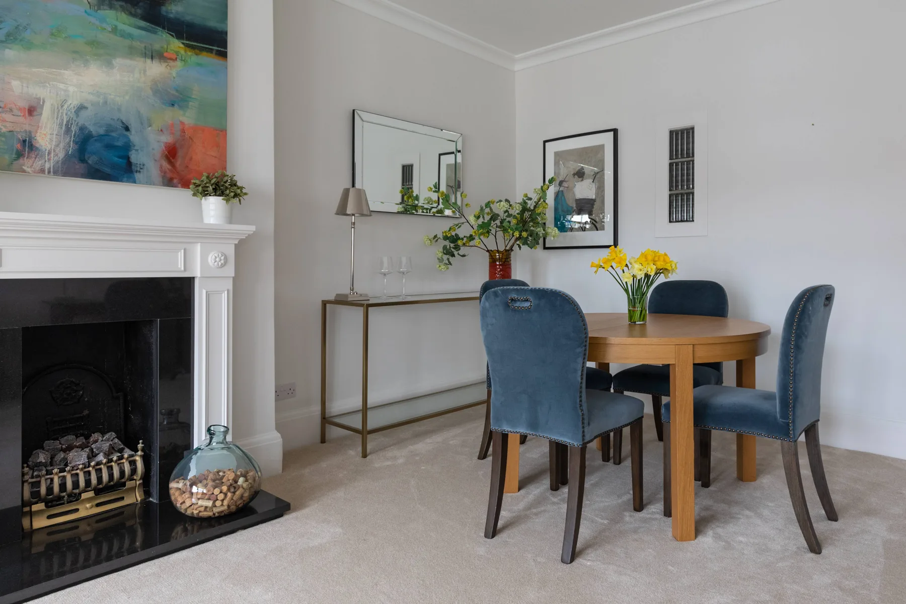 A dining area with a round wooden table, blue seating, and a fireplace.
