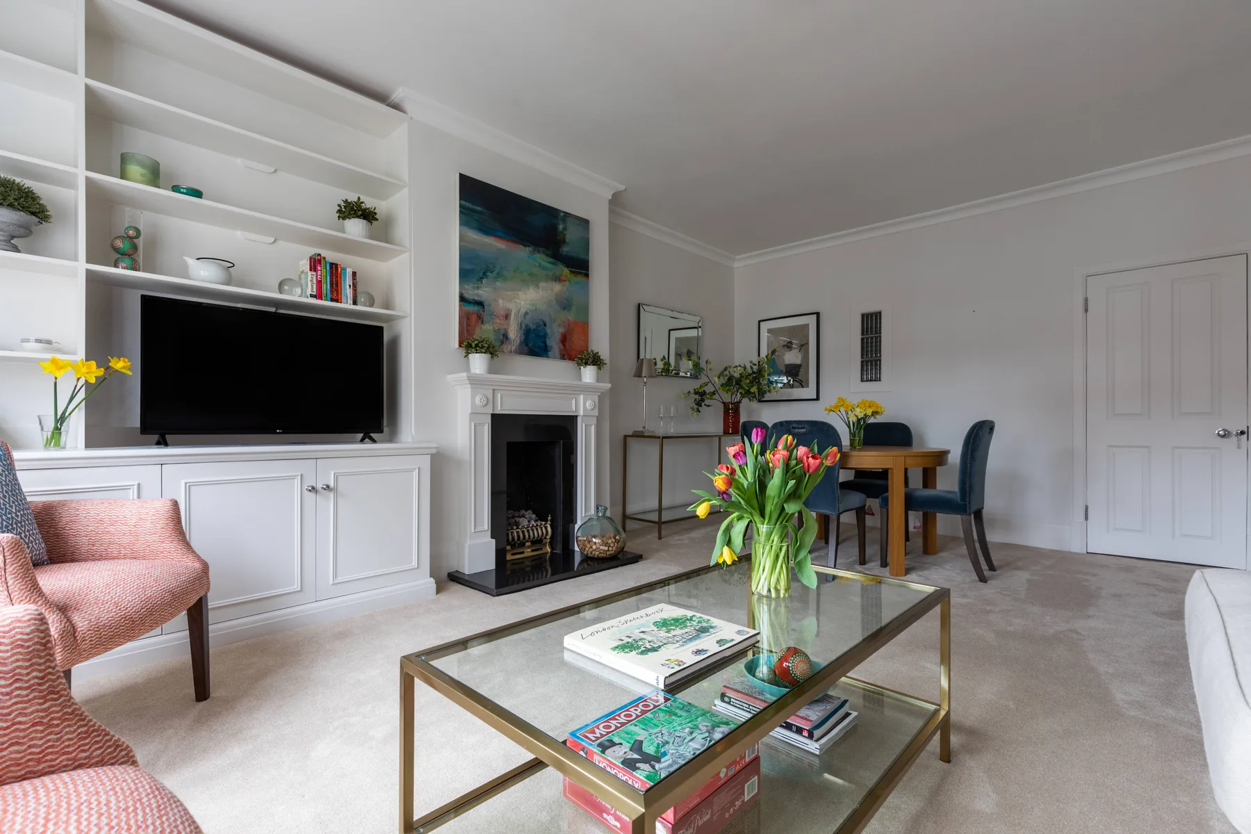 A bright living room with built-in shelving, a fireplace, and a glass coffee table.