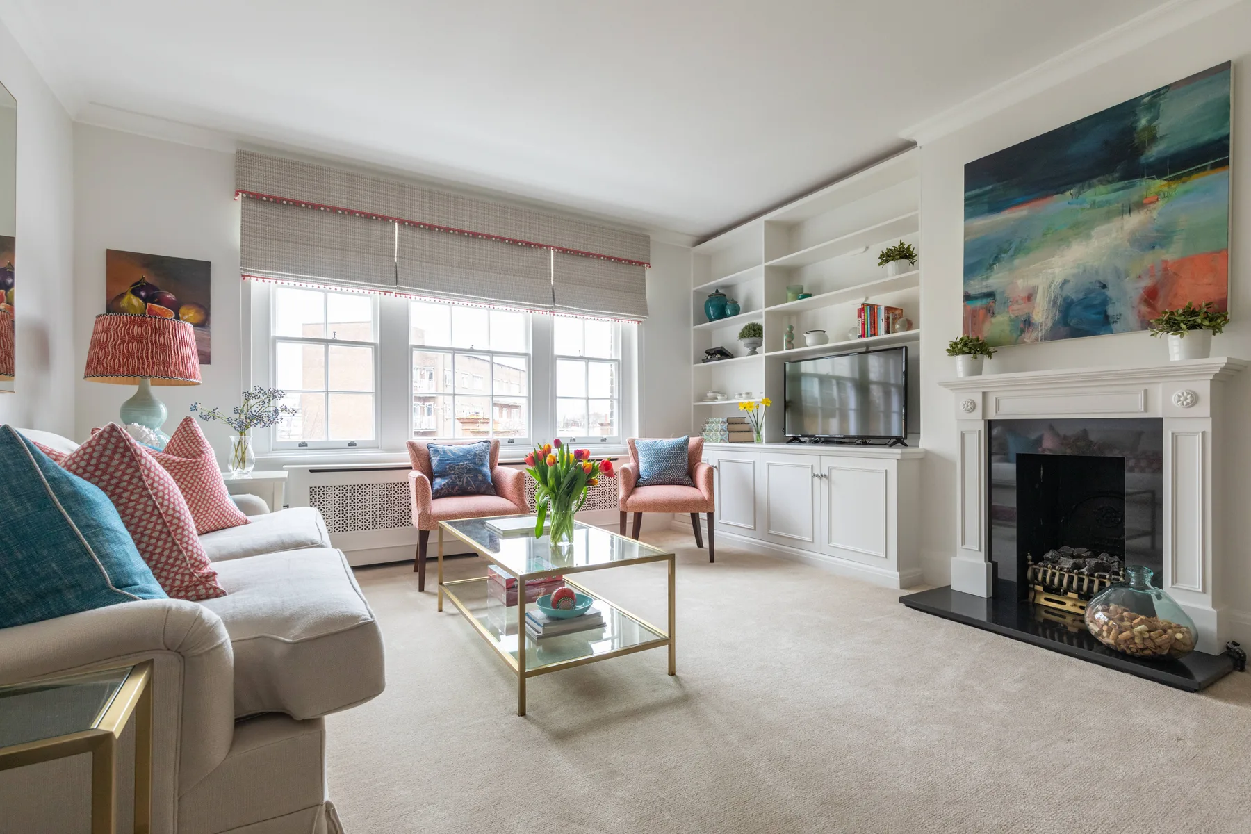 Bright living room with seating, a television, and a fireplace.