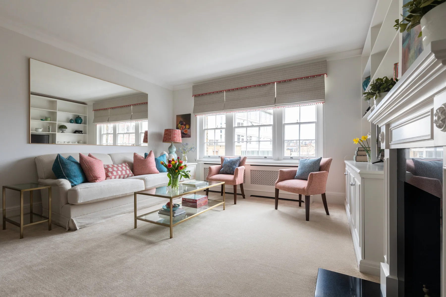 A bright living room with seating around a glass coffee table and large windows.