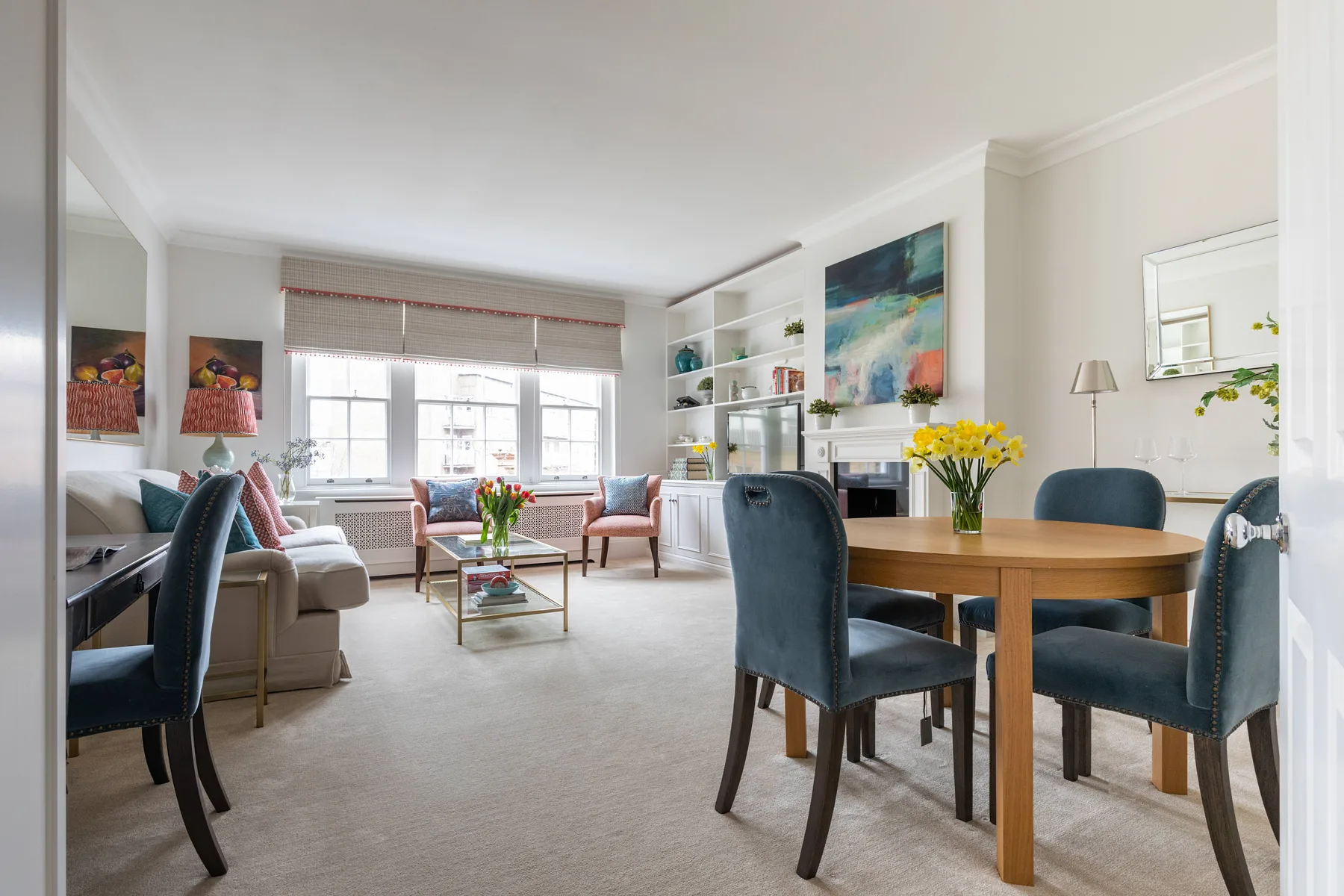 A bright living and dining area with seating arranged around a wooden table.