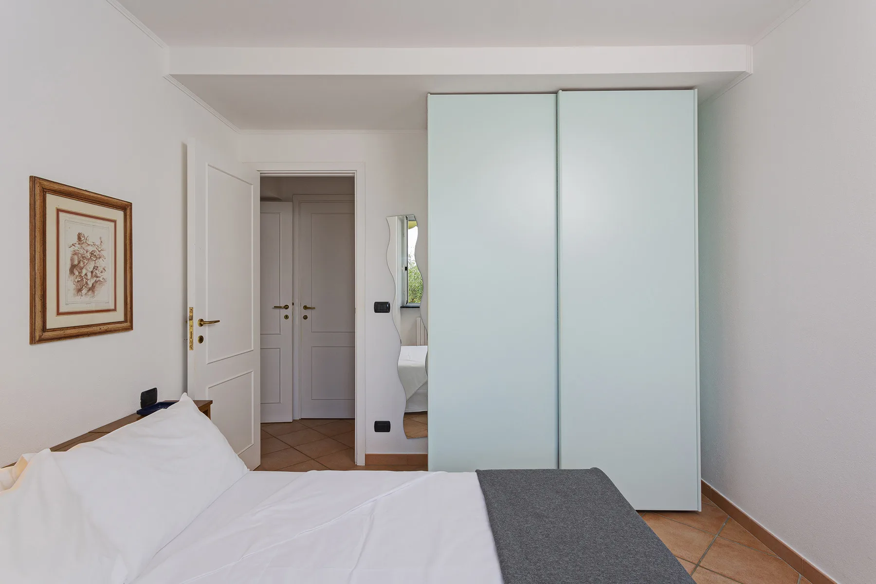 A bedroom with a white bed and a sliding-door wardrobe.