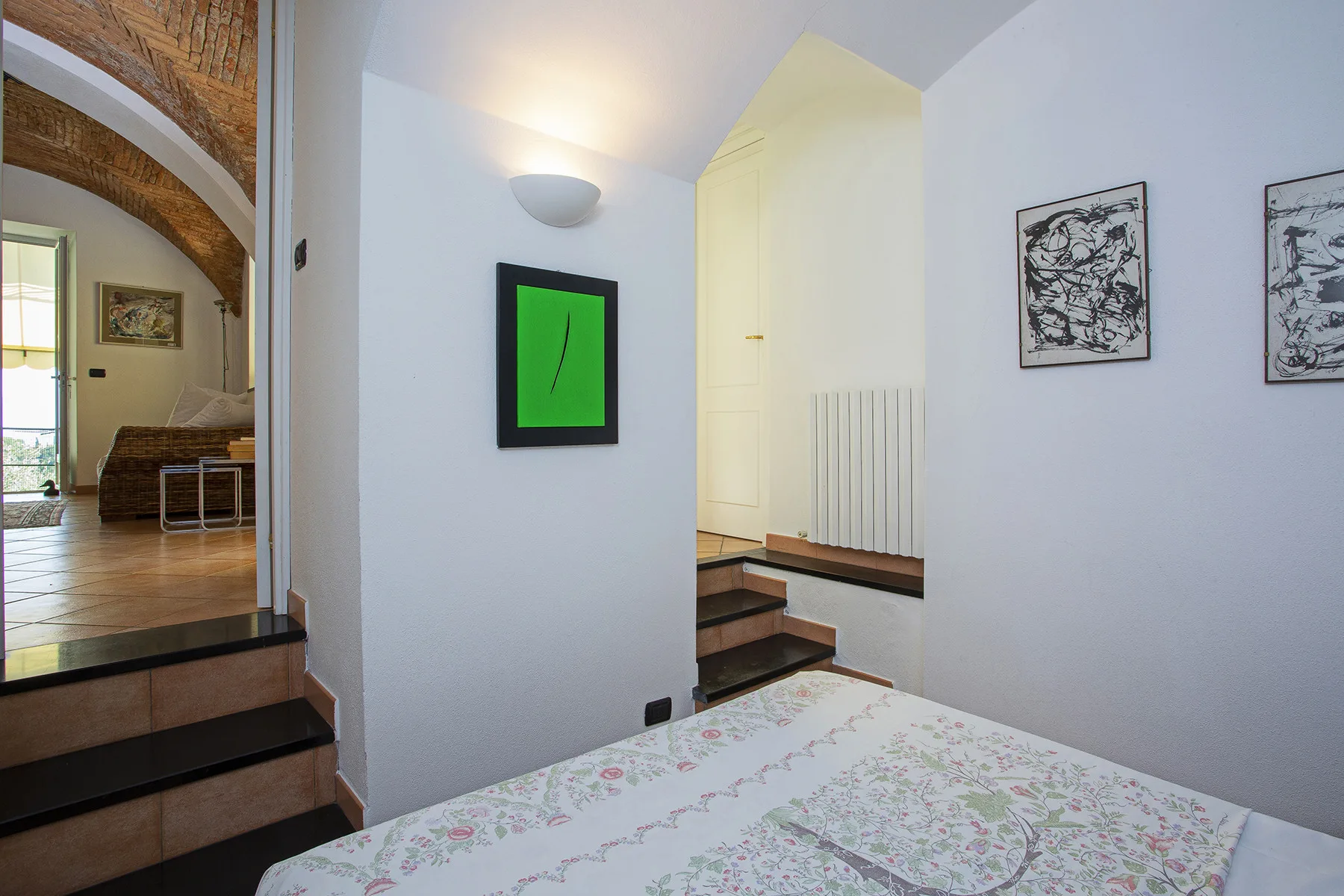 Un dormitorio da a un pasillo con escaleras y cuadros enmarcados.