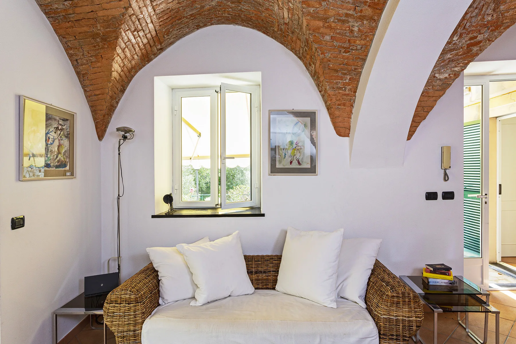 A bright sitting area with wicker seating beneath exposed brick arches.