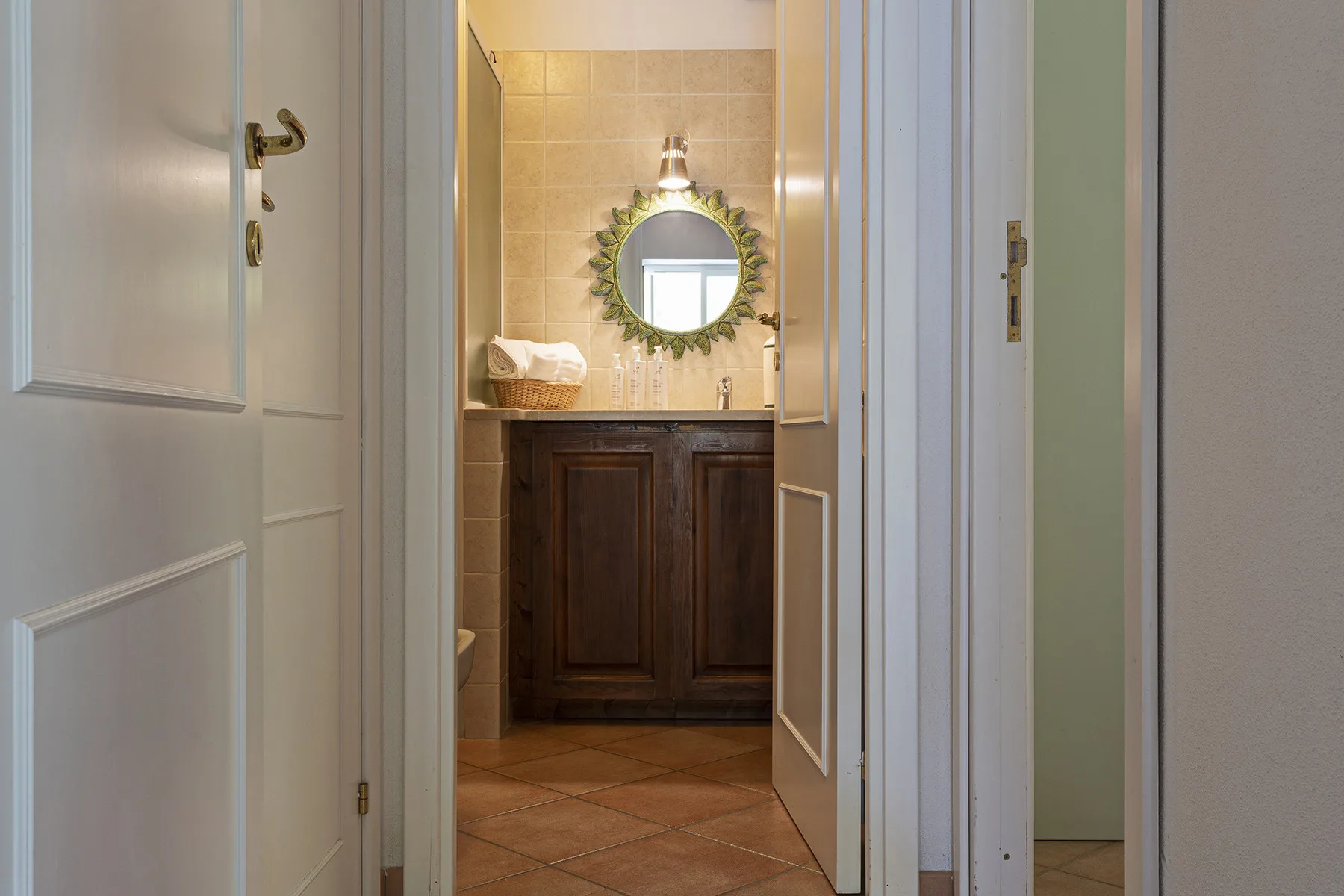 A bathroom vanity is visible through an open doorway, with a round mirror above the sink.