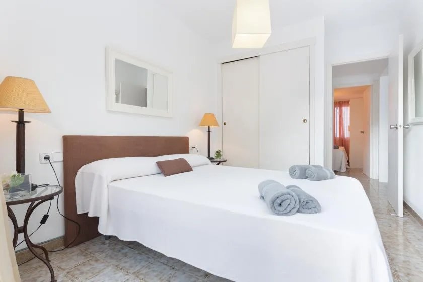 Un dormitorio luminoso con una cama tendida y toallas dobladas.
