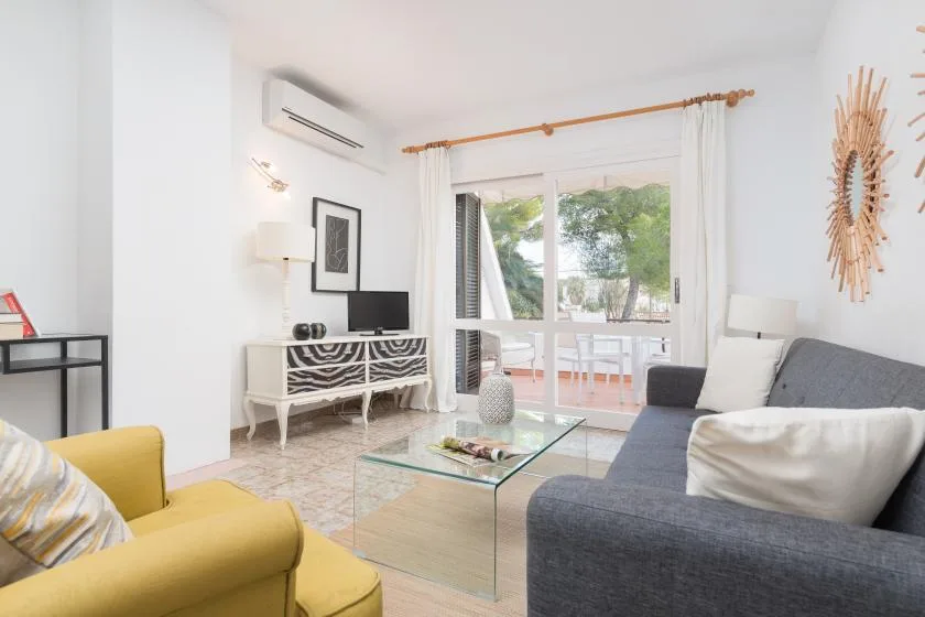Una sala luminosa con asientos, una mesa de centro de vidrio y ventanales.
