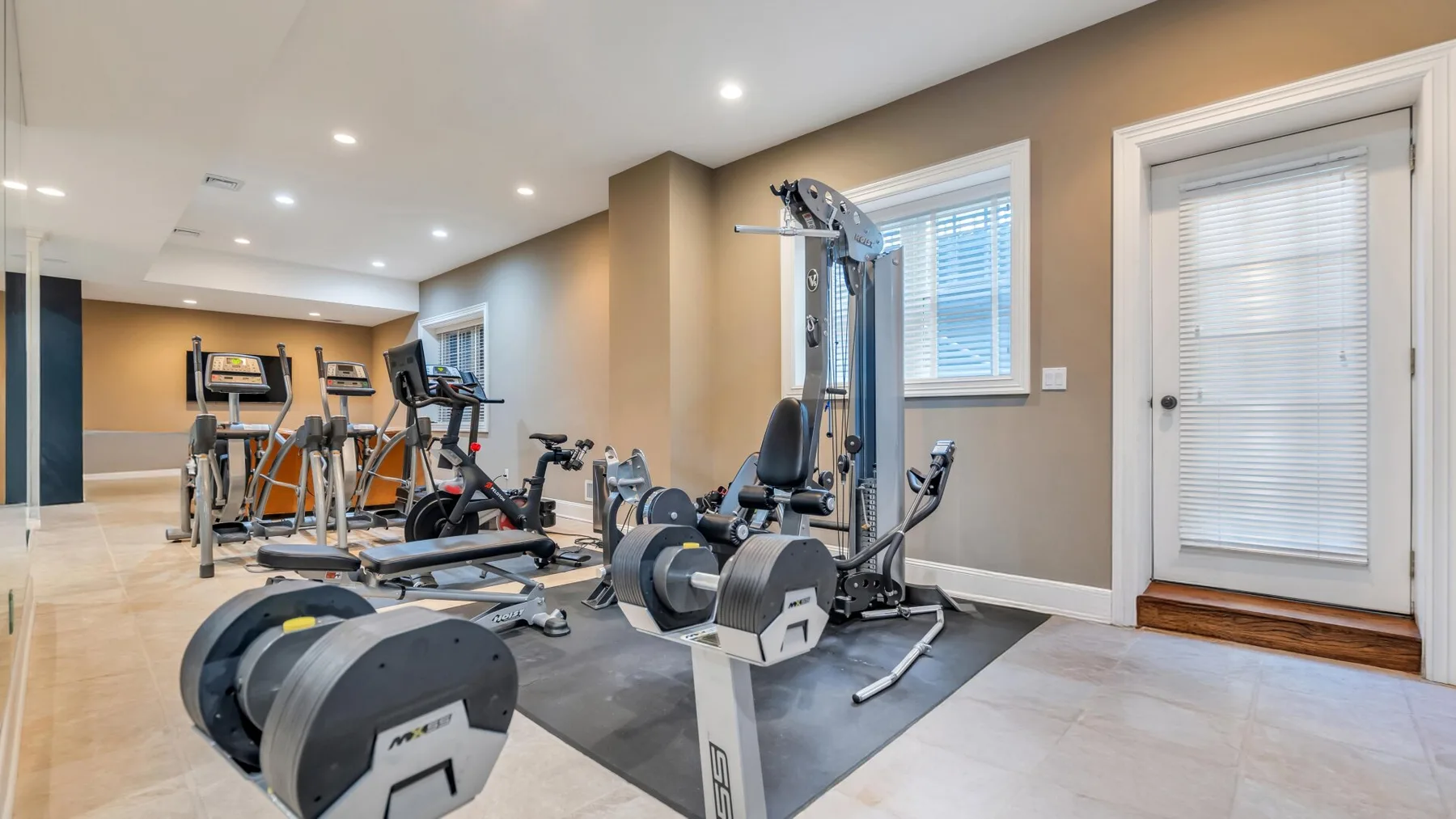 A home gym with exercise equipment arranged on a padded workout area.
