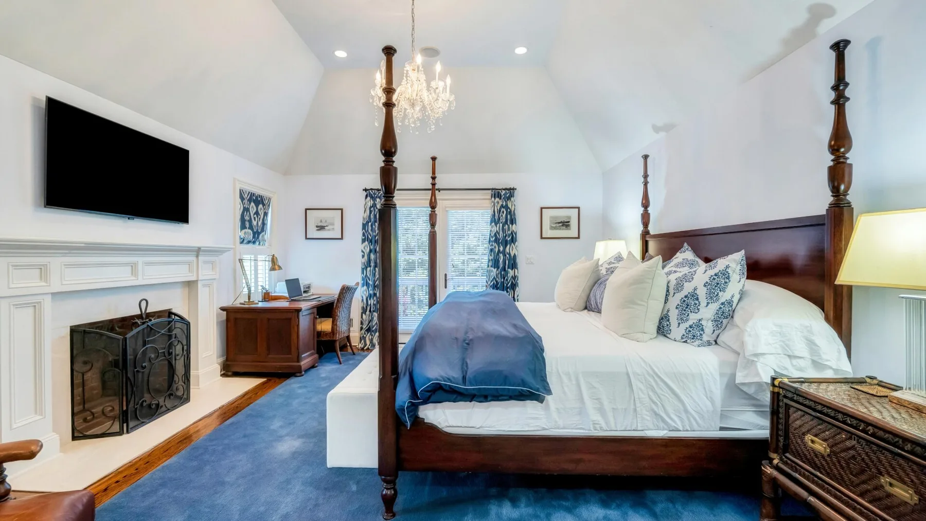 A bedroom with a large bed, blue bedding, and a fireplace.