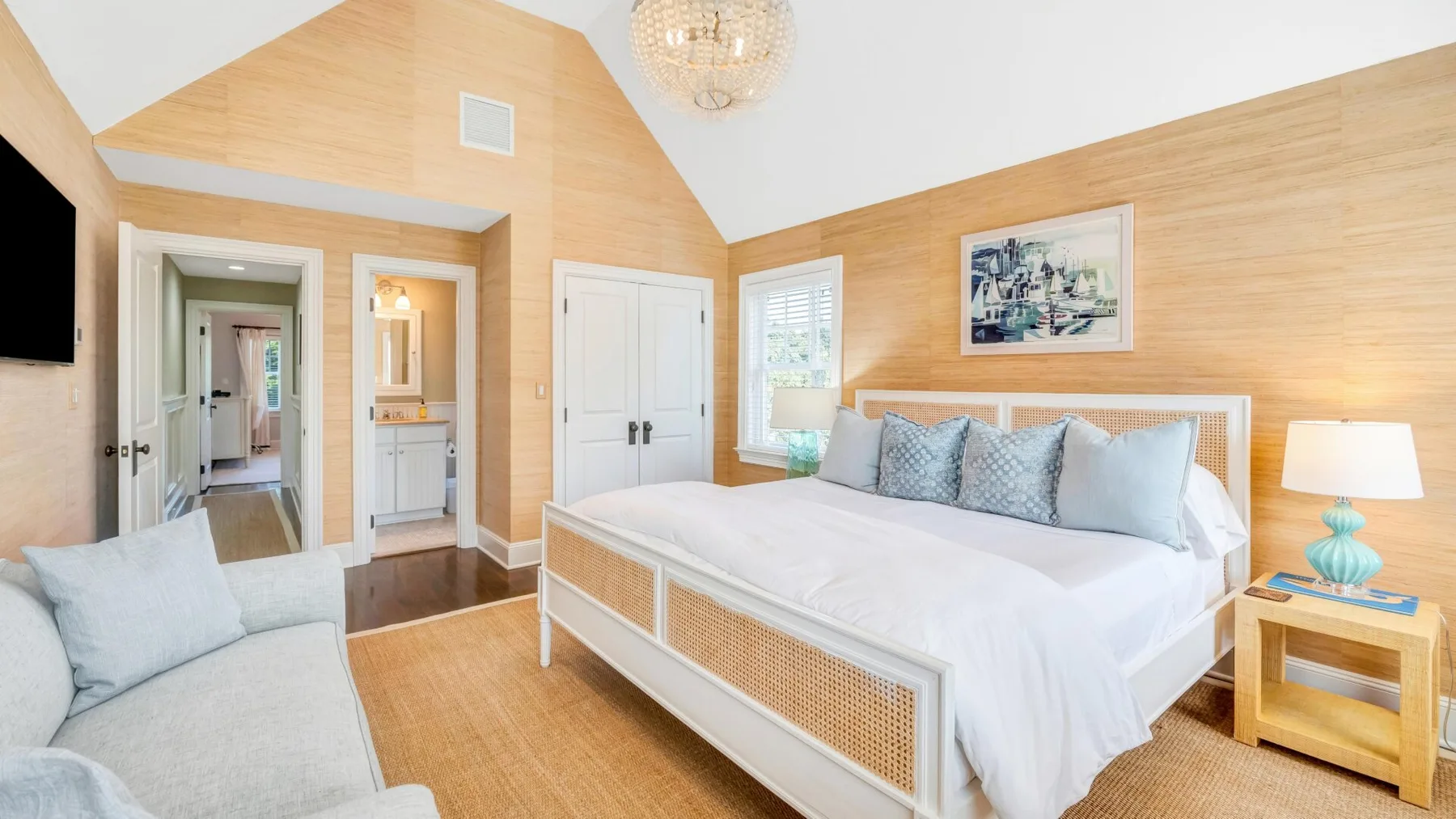 A bright bedroom with a large bed and light wood-paneled walls.