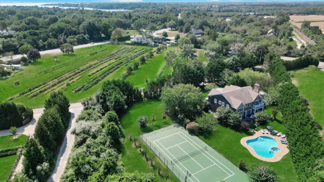 Aerial view of a country property with a tennis court and swimming pool.