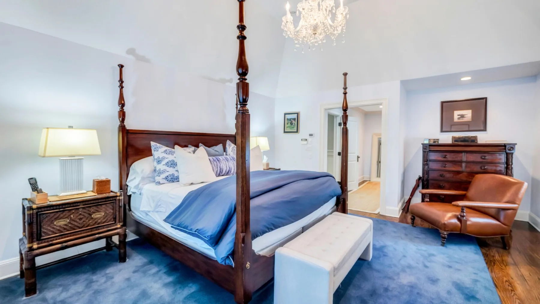 A bedroom with a four-poster bed and a blue rug.