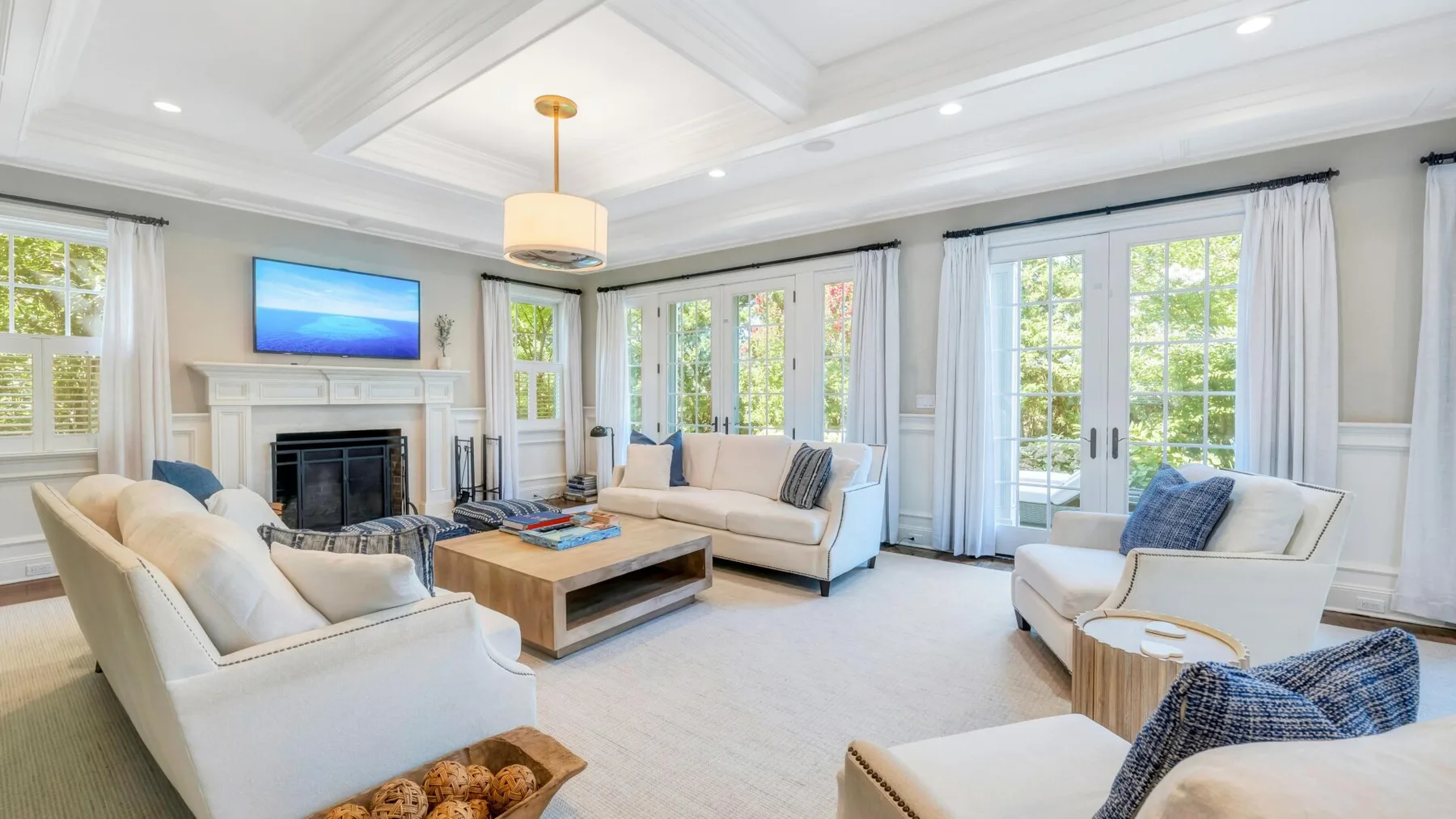 A bright living room has seating arranged around a coffee table beside large windows.