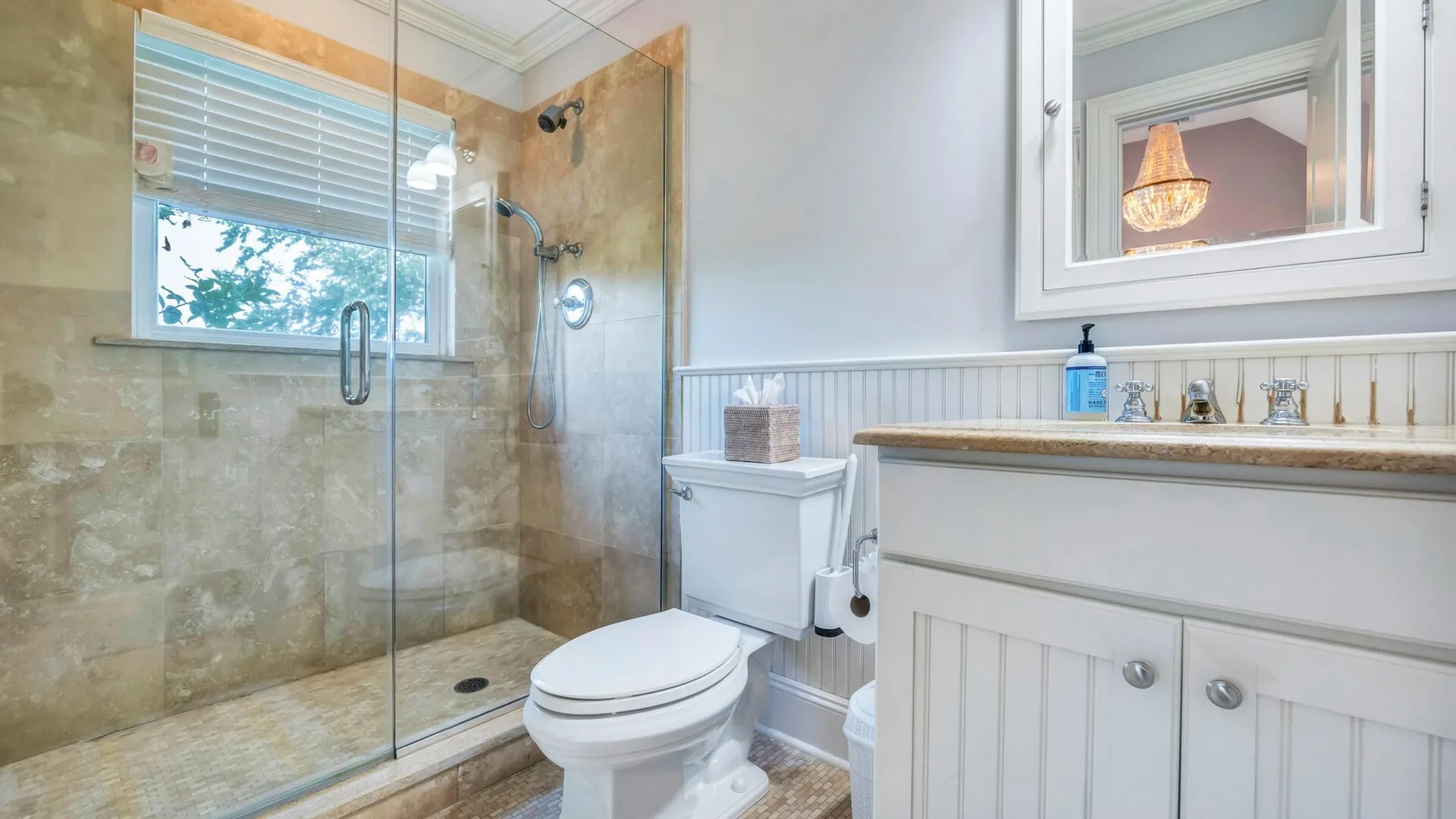 A bright bathroom with a glass shower, toilet, and sink vanity.