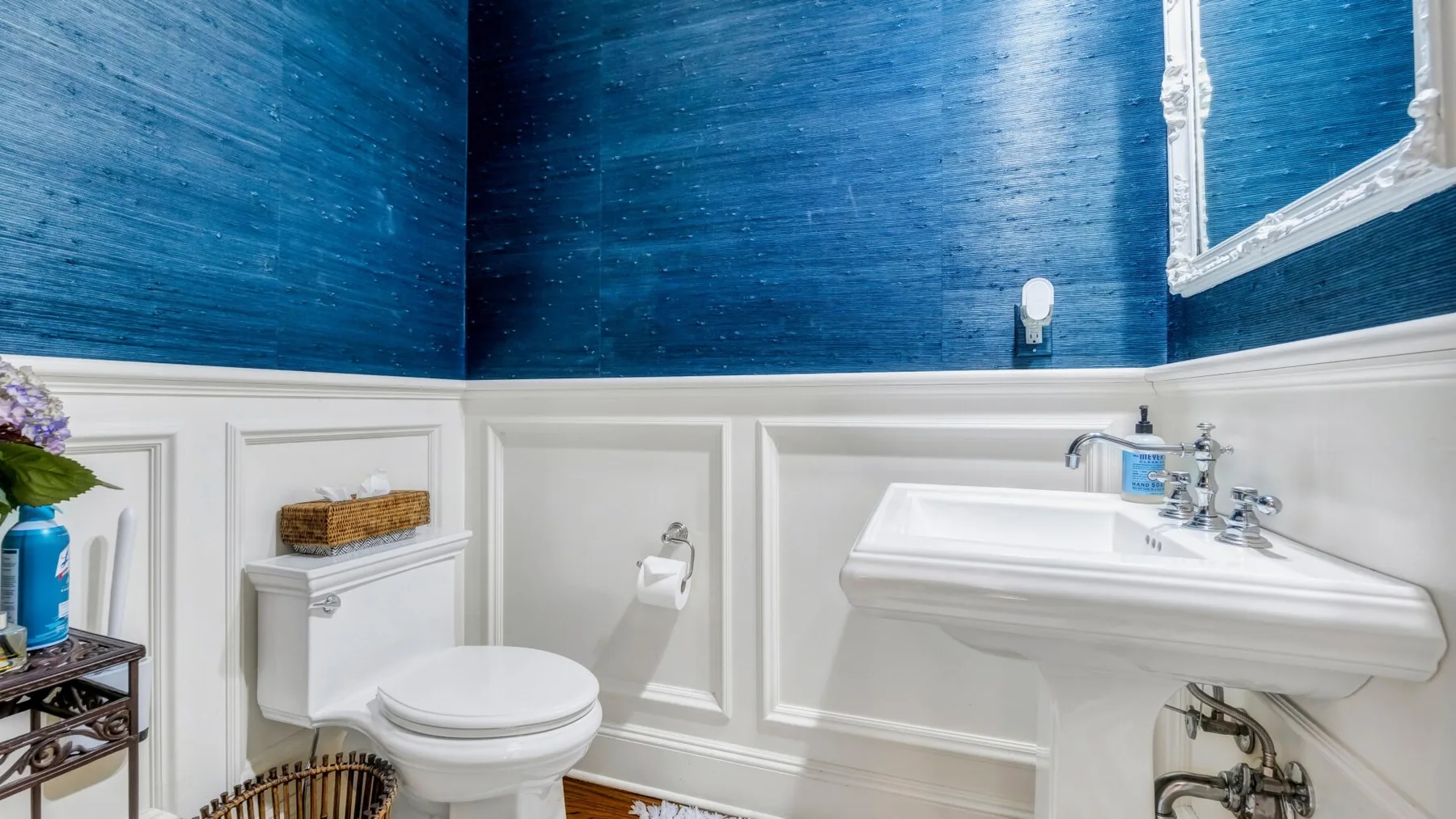 A bathroom with a white sink and toilet against blue walls.