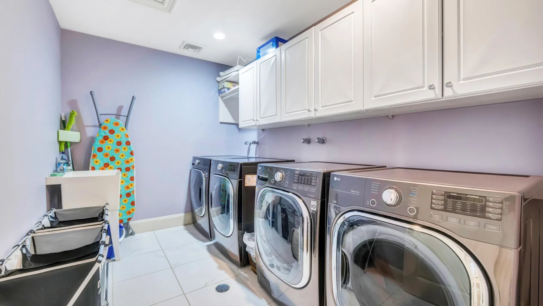 Laundry room with washing machines beneath white cabinets.