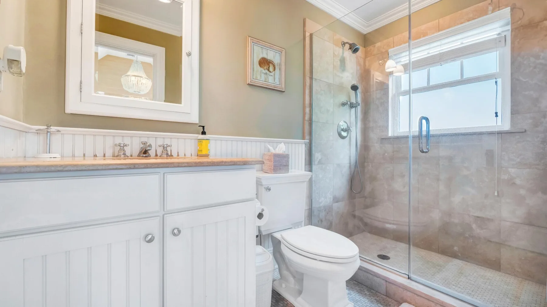 A bathroom with a vanity, toilet, and glass-enclosed shower.