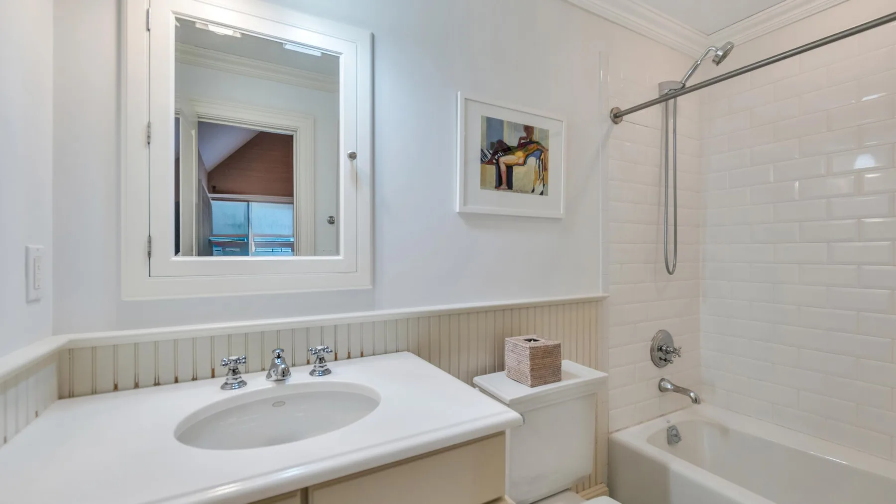 A bright bathroom with a sink, mirror, and bathtub with a shower.