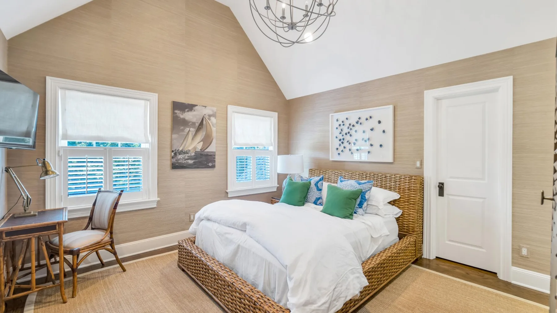 A bright bedroom with a bed, windows, and a white door.
