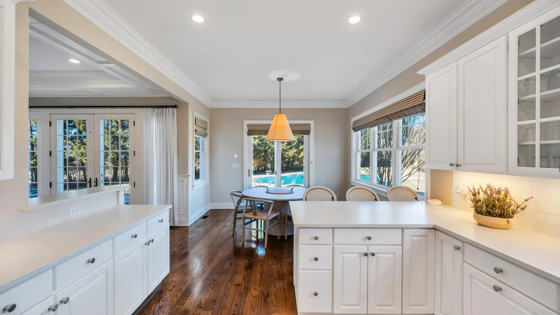 A bright kitchen opens onto a dining area with large windows.