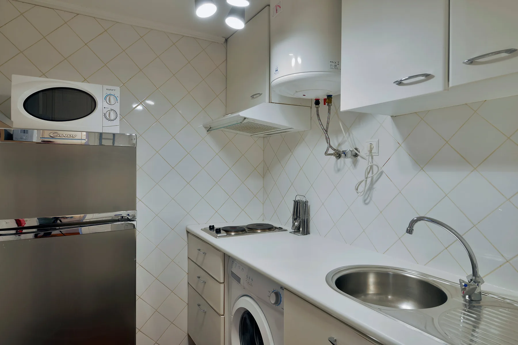 A compact kitchen with a refrigerator, countertop, and sink.