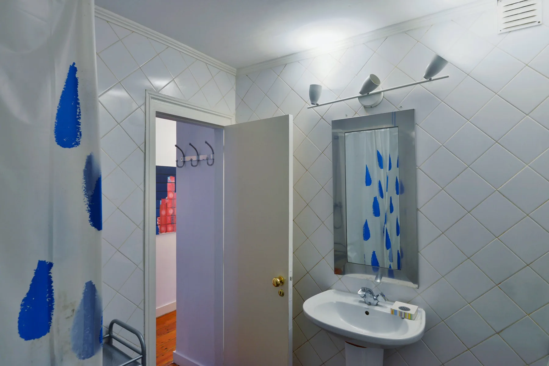 A tiled bathroom with a wall mirror and pedestal sink.
