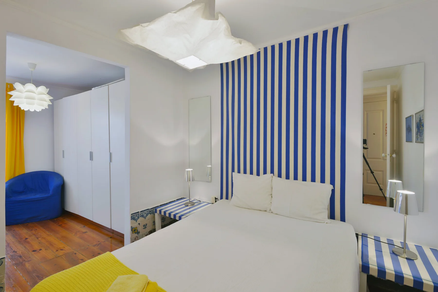 A bedroom with a white bed and a blue-and-white striped wall.