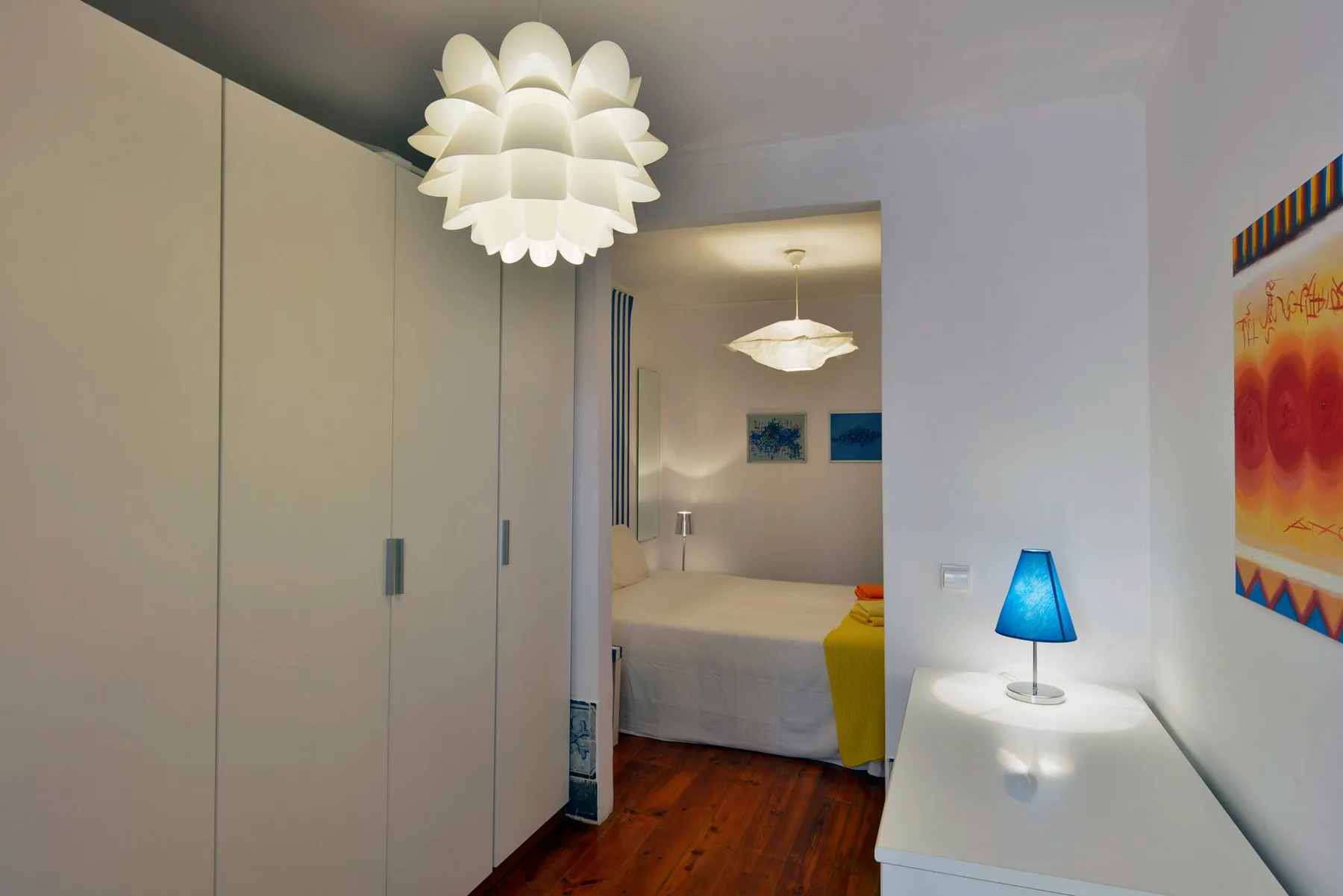 A bedroom with a bed, bedside lamps, and built-in wardrobes.