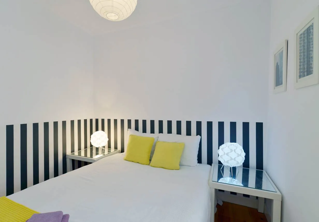 A bedroom with a bed, yellow pillows, and striped wall paneling.