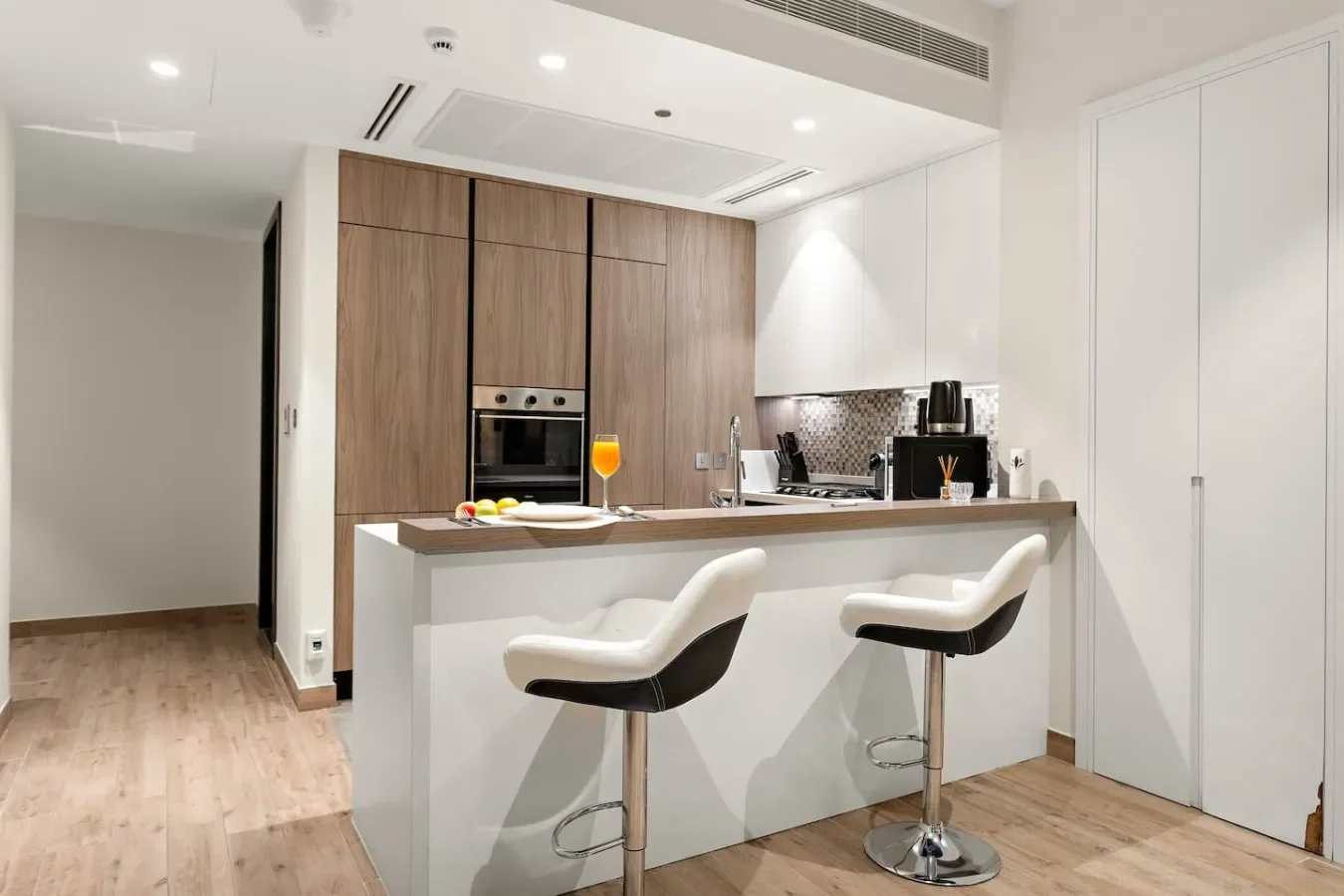 Una cocina moderna con una barra y dos taburetes.