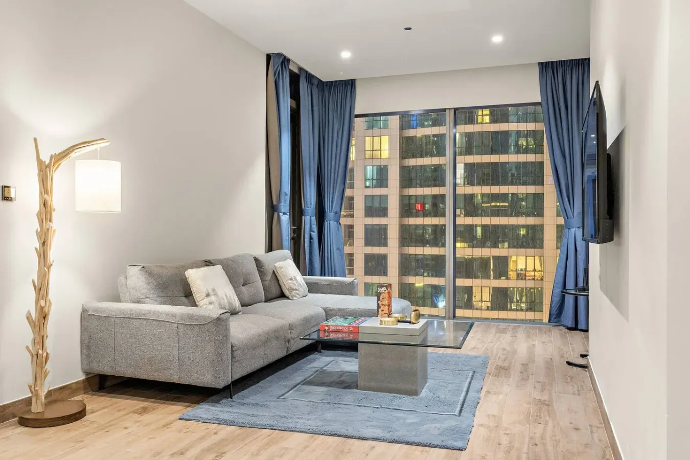 Una sala de estar con asientos, una mesa de centro y grandes ventanas con cortinas.