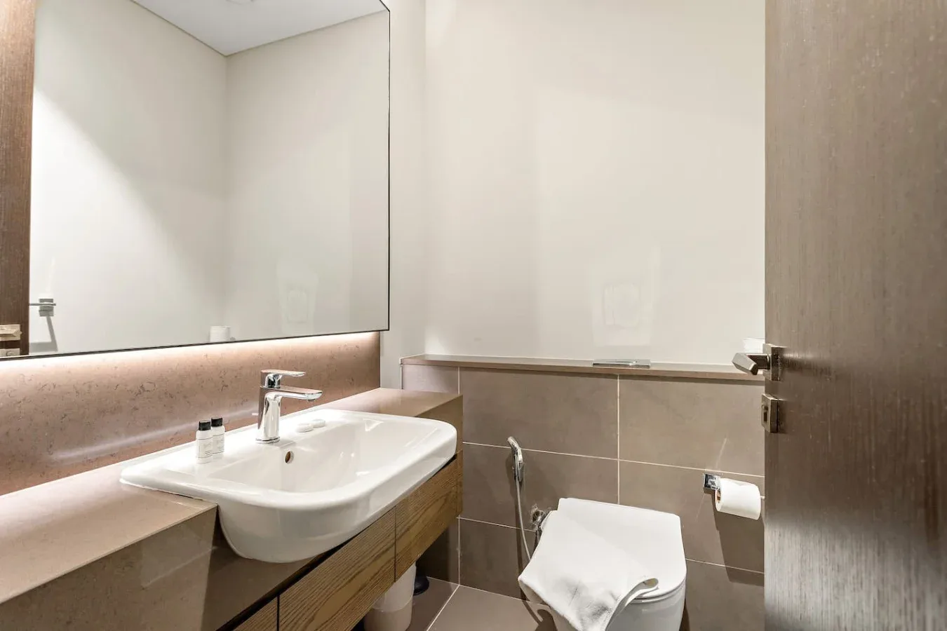 Un baño con lavabo blanco, espejo e inodoro.