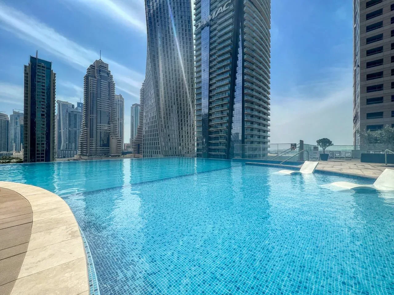 Una piscina al aire libre está rodeada de edificios altos bajo un cielo despejado.