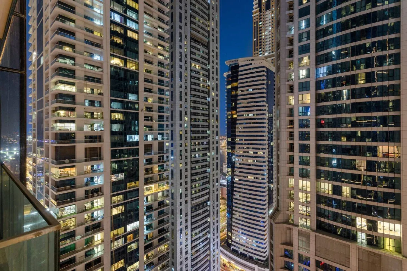 Una vista nocturna de la ciudad muestra edificios altos iluminados contra el cielo azul oscuro.