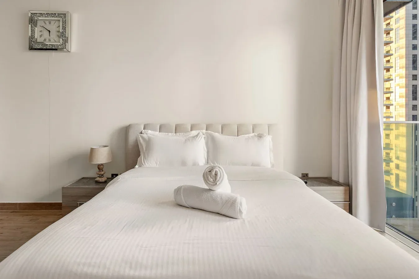 Un dormitorio luminoso con una cama tendida y una ventana al lado.