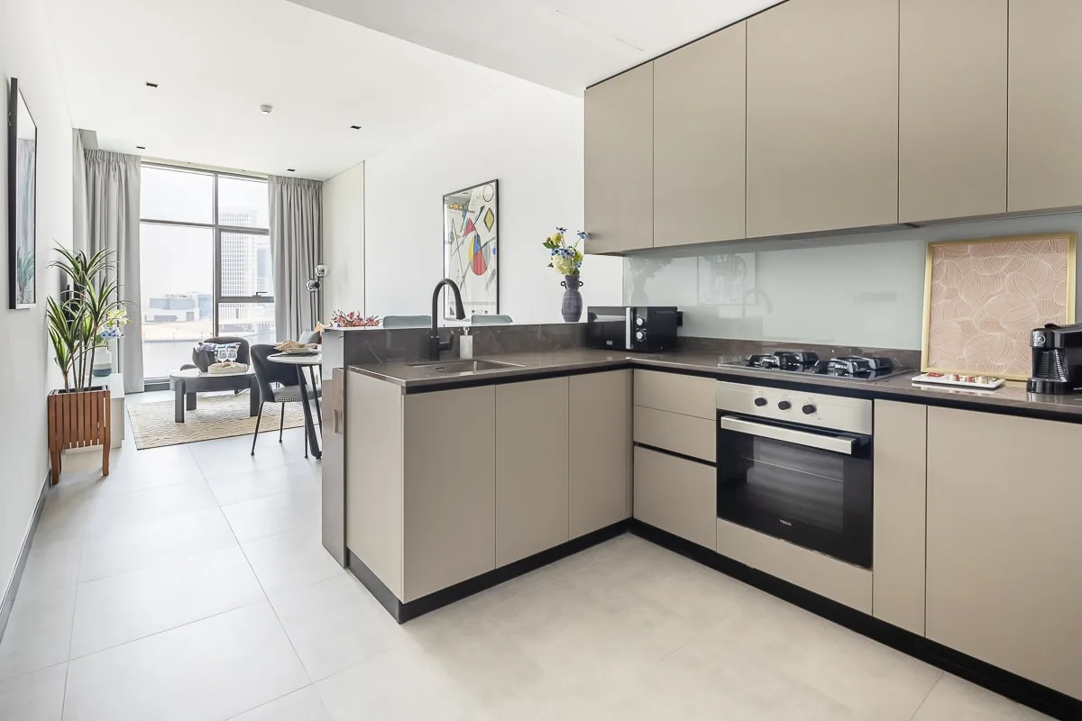 Una cocina moderna se abre a un comedor, con grandes ventanas al fondo.