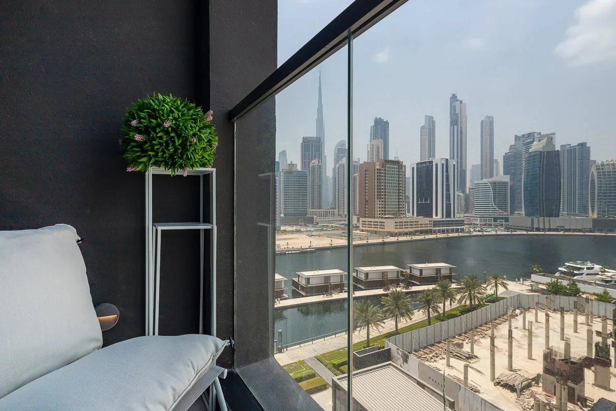 Una zona de asientos junto a una ventana de cristal da a un horizonte urbano junto al agua.