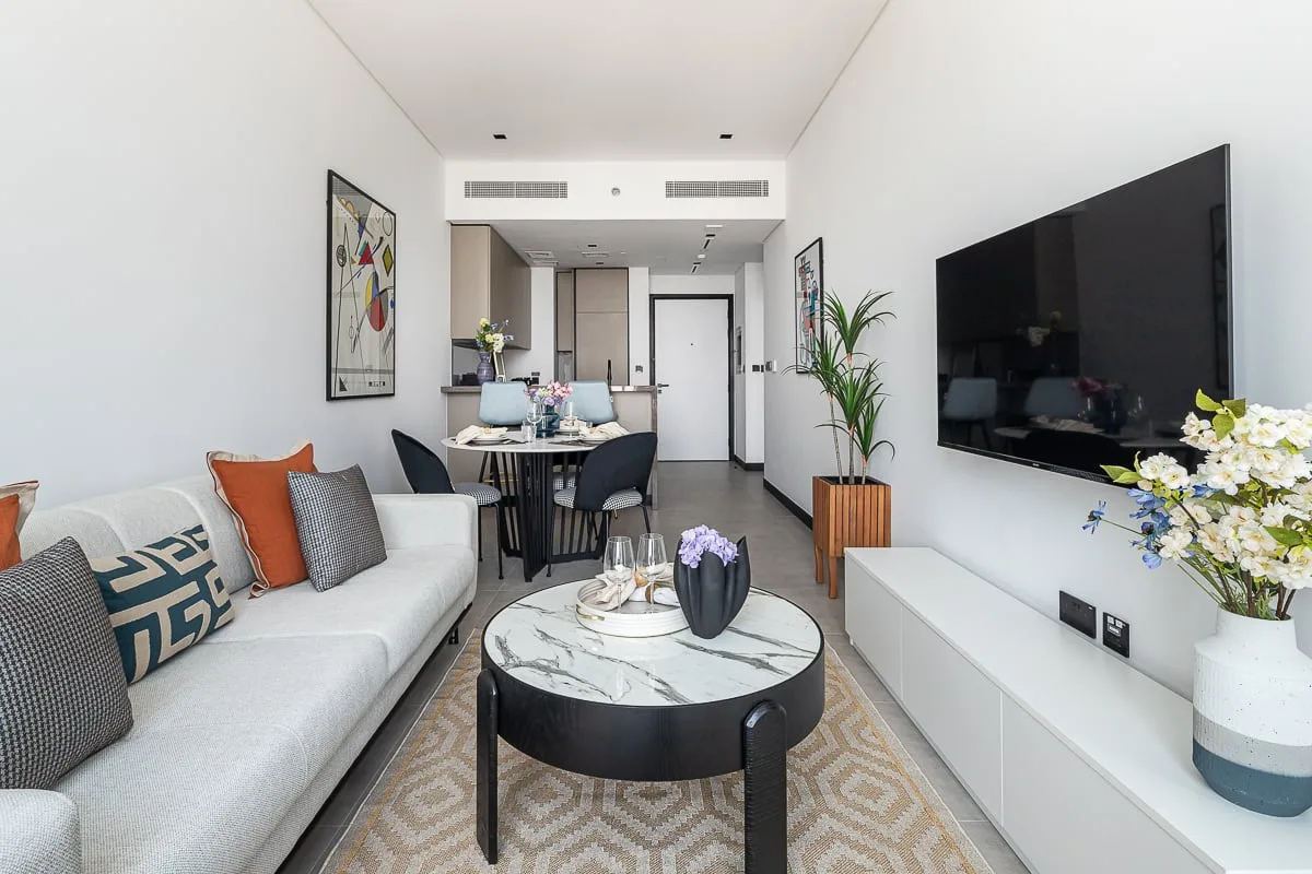 A bright living room with a sofa, coffee table, and wall-mounted television.