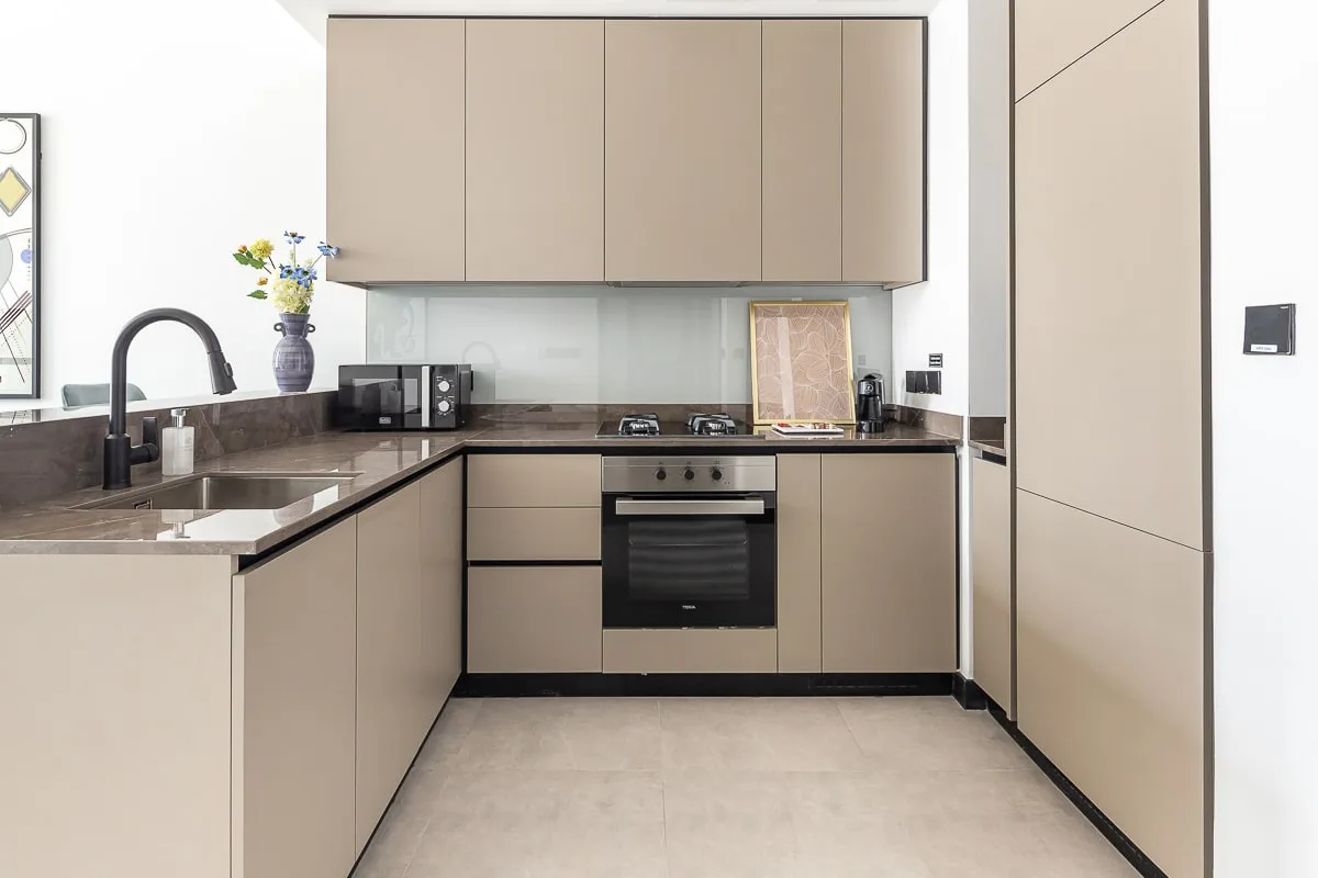 Una cocina moderna con gabinetes claros, encimeras oscuras y electrodomésticos integrados.