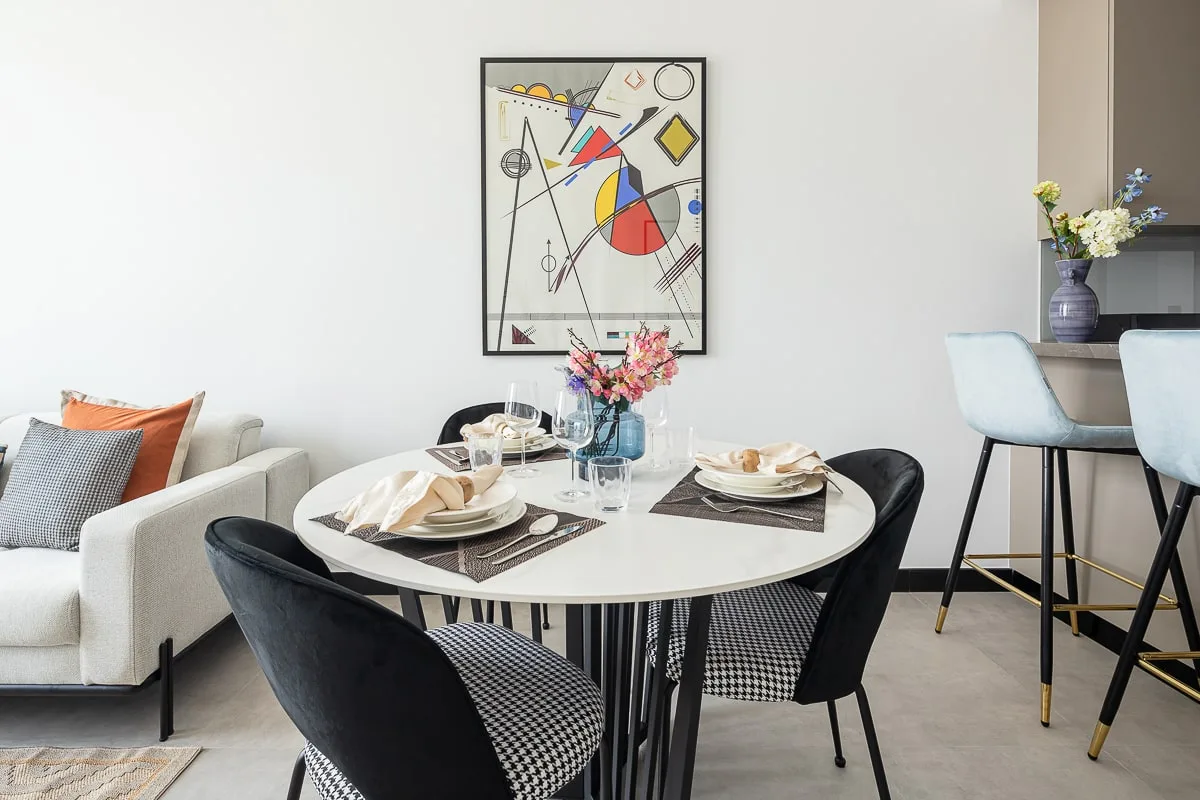 Comedor con la mesa puesta y una obra abstracta enmarcada en la pared.