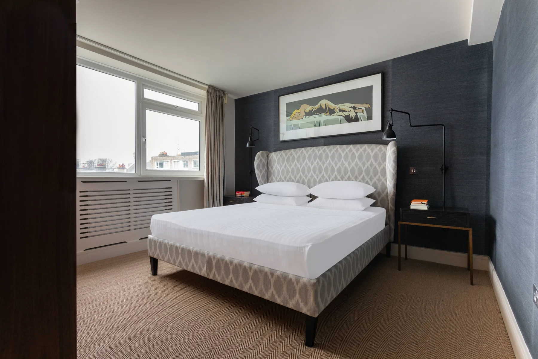 A bedroom with a bed, bedside tables, and a large window.